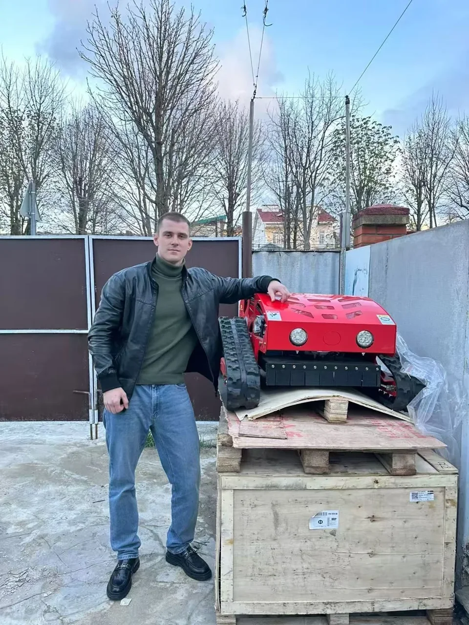 Customer standing beside a mower in a wooden delivery crate